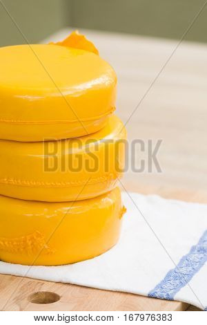 Three big organic cheese heads in yellow vacuum package laying on top of each other in the farm kitchen. Food concept
