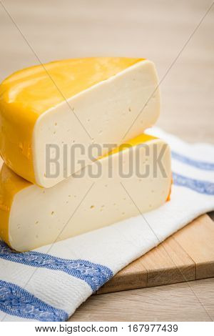 Two big organic cheese heads in yellow vacuum package laying on top of each other in the farm kitchen. Food concept