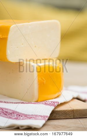 Two big organic cheese heads in yellow vacuum package laying on top of each other in the farm kitchen. Food concept
