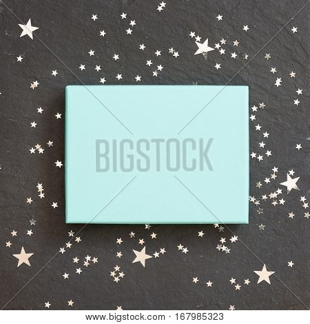 rectangular light blue box on black background with silver stars decorations. Holiday greetings. Engagement. turquoise on black board.