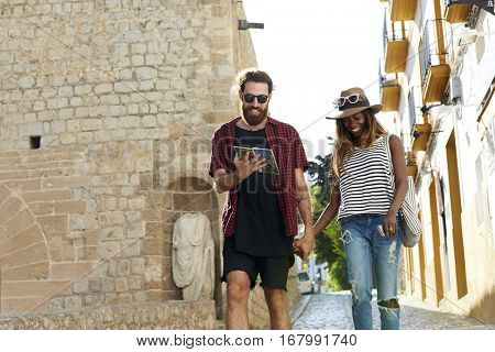 Couple on holiday walk, reading a guidebook, three quarters