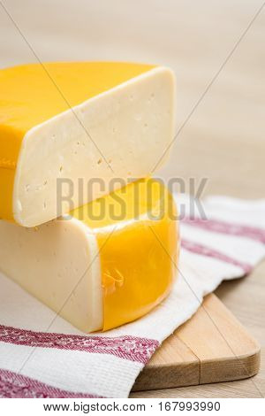 Two big organic cheese heads in yellow vacuum package laying on top of each other in the farm kitchen. Food concept