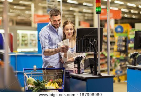 shopping, sale, consumerism and people concept - happy couple buying food at grocery store or supermarket self-service cash register