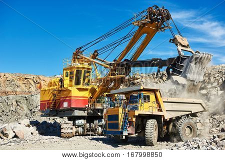 excavator loading granite or ore into dump truck at opencast