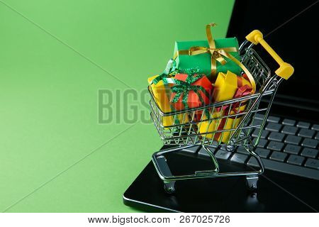 Ciber Monday Concept - Trolley Cart With Christmas Presents On Notebook, Green Background
