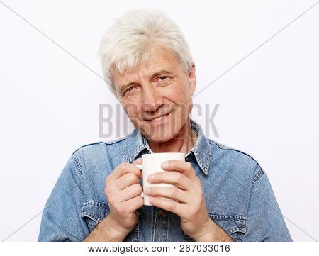 lifestyle, food and people concept: Handsome mature man hoding a cup of coffee or tea