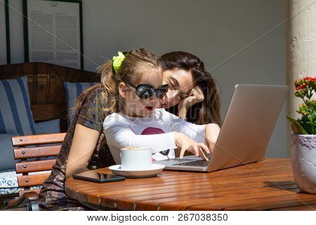 Happy Girl With Sunglasses Touching Laptop Keyboard Next To Mother