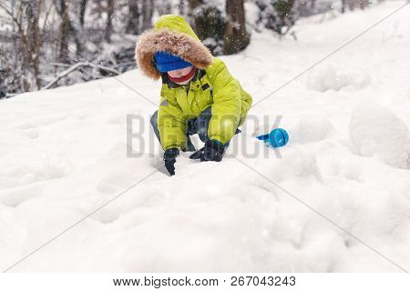 Happy Child In Warm Clothing Playing With Snow. Child In Warm Clothing In Winter. Kid Making Snowbal