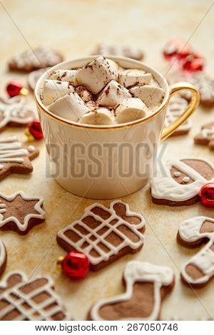 Cup of hot chocolate with tasety marshmellows. Fresh baked Christmas shaped gingerbread cookies on sides. With Xmas decorations. View from above.