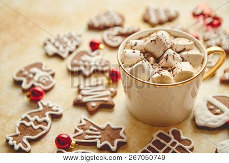 Cup of hot chocolate with tasety marshmellows. Fresh baked Christmas shaped gingerbread cookies on sides. With Xmas decorations. View from above.