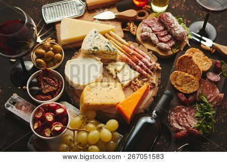 Huge assortment of various tasety spanish, french or italian apertizers. Cheese, meat, olives, stuffed peppers, bread, sticks. Placed on rusty dark background. View from above.