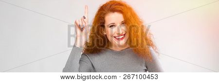 Charming Young Girl With Red Hair. A Young Girl In A Gray Sweater. Young Girl On A Gray Background. 