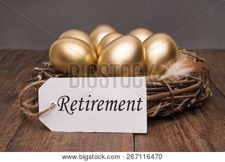 Nest With Golden Eggs With A Tag And A Word Retirement On A Wooden Background. The Concept Of Succes