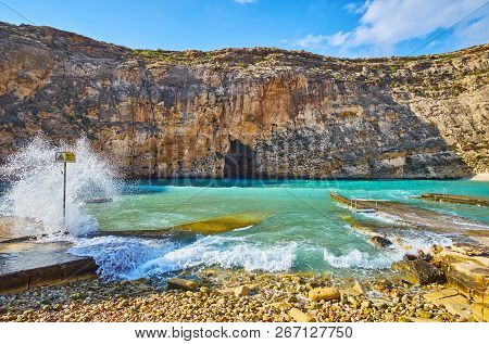 The Foamy Waves Splash Against The Beach Of Dwejra Inland Sea, The Massive Rock With Blue Hole Grott