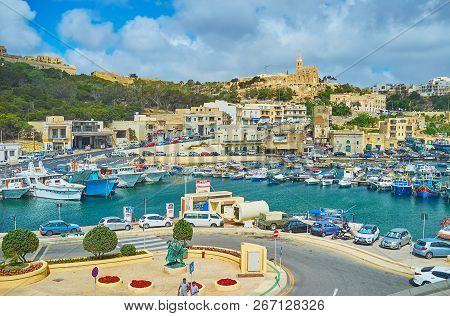 Ghajnsielem, Malta - June 15, 2018: Mgarr Harbour With Old Fishing Boats Is Surrounded By Tall Hills