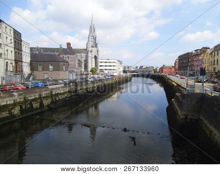 Nice Houses Anlong A River In Cork. Parking Cars And A Church Is Also Visible.