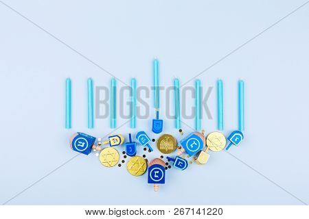 Blue Background With Menora Made Of Dreidels And Chocolate Coins. Hanukkah And Judaic Holiday Concep