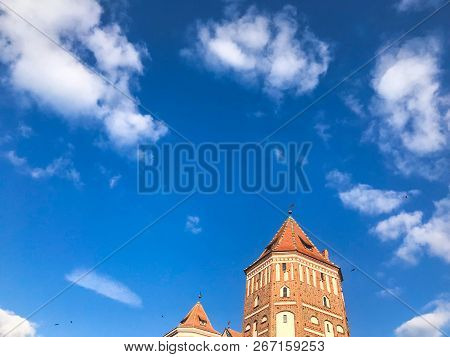 Towers And Spiers Of A High Medieval Stone Old Ancient Beautiful Castle Against A Blue Sky.