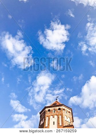Towers And Spiers Of A High Medieval Stone Old Ancient Beautiful Castle Against A Blue Sky.