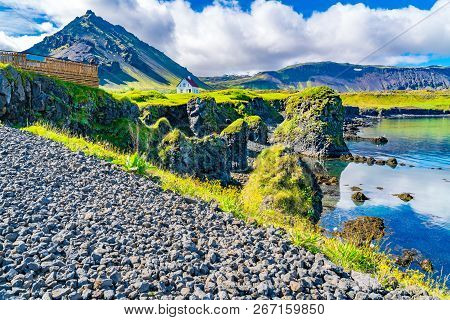 Volcanic Landscape Of Basalt Rocks Formation With A Beautiful House And The Mountain Stapafell At Ar