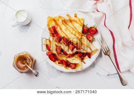 Сrepes With Fresh Strawberries And Caramel On Light Concrete Old Table Background. Top View.