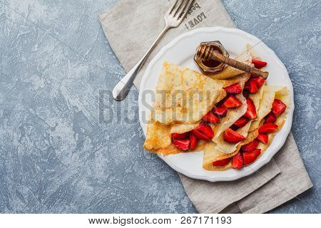 Сrepes With Fresh Strawberries And Honey On Gray Concrete Background. Top View.