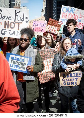 March For Our Lives: Participants, including a woman holding an infant, in the march to end gun violence on 6th Ave hold signs with various phrases, NEW YORK MAR 24 2018.