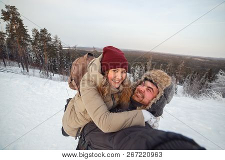 Happy Couple In Winter Clothes Tkaing Selfie On A Background Of Snow-covered Winter Pine Forest