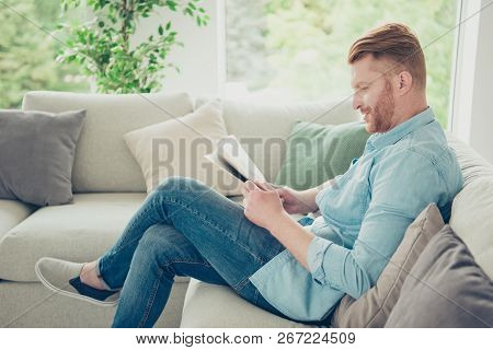Stylish Trendy Man In Blue Shirt Look At Newspaper Make Nice Glad Smile Sit On Cosy Sofa In Light Ho