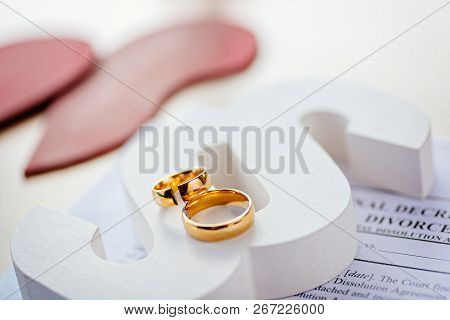 Two Broken Wedding Rings On Wooden Paragraph.