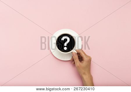 Female Hand Holding A White Cup With Black Coffee On A Pink Background. Question Mark . Flat Lay, To