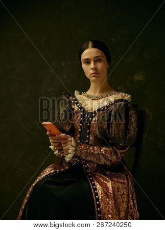 Portrait Of A Girl Wearing A Princess Or Countess Dress With Mobile Phone Over Dark Studio