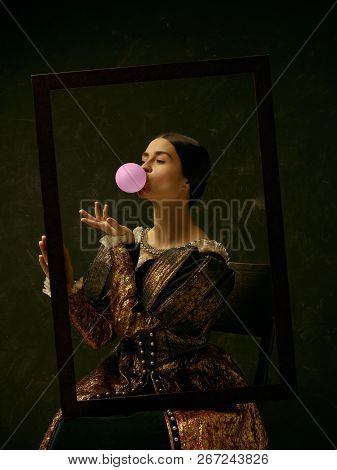 Portrait Of A Girl Wearing A Princess Or Countess Dress Over Dark Studio. Portrait Through Picture F
