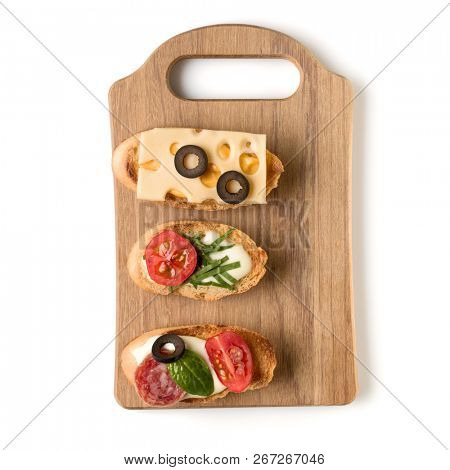 Open faced sandwich canape or crostini on a wooden serving board isolated on white background closeup. Top view.