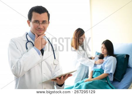 Portrait Of Profressional Doctor With Stethoscope While Female Doctor Take Care Her Patient.