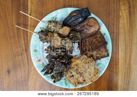 Komo Beef Satay, Spleen, Tongue, Chunks Beef Meat, Veal Brain Crisp, And Beef Lung Crisp On A Plate