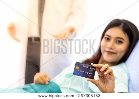 Portrait of Young adult female Patient with credit card in bed of hospital ward