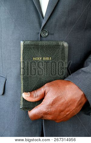 Black Man Praying With Hands Clasped Together Holding The Holy Bible After Prayer At A Service In Ch