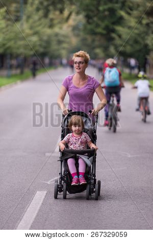 young healthy mother jogging while pushing a baby stroller at city park