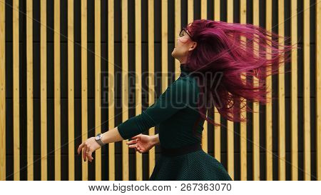 Cute Young Girl Dancing On Background Of A Simple Geometric Pattern. Girl Has Eggplant Hair Flying I
