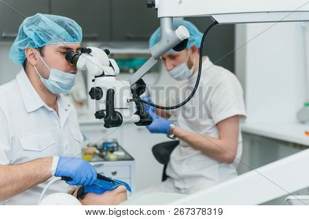 Doctor Used Microscope. Dentist Is Treating Patient In Modern Dental Office. Operation Is Carried Ou