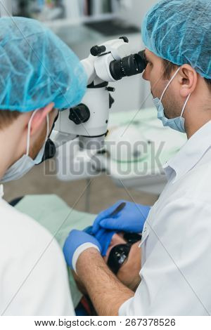 Doctor Used Microscope. Dentist Is Treating Patient In Modern Dental Office. Operation Is Carried Ou