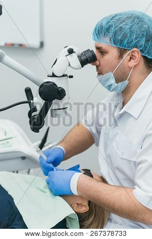 Doctor Used Microscope. Dentist Is Treating Patient In Modern Dental Office. Operation Is Carried Ou