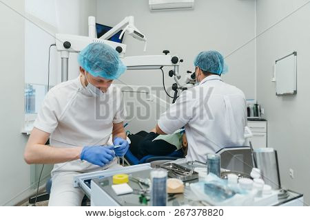 Doctor Used Microscope. Dentist Is Treating Patient In Modern Dental Office. Operation Is Carried Ou