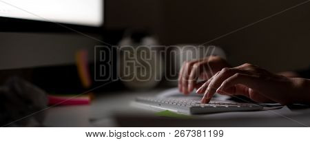 Workaholic Hand Typing Keyboard In Dark Late Night With Computer Screen Light, Clock, Coffee Cup And
