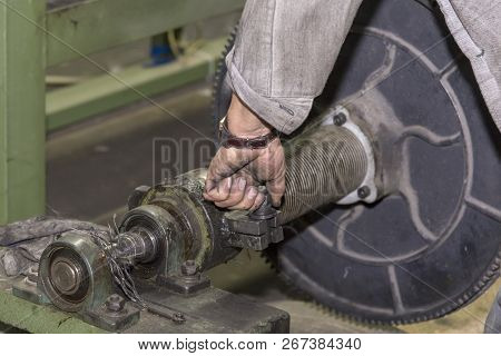 A Mechanic Repairs A Machine In A Factory.