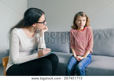 Professional Child Psychologist Talking With Child Girl In Office.