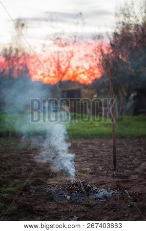 Close Up Of Burning Garden Bonfire With Pitchfork.