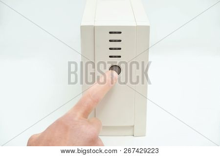 The Index Finger Is Pressing On The Start Button Of The Uninterrupted Power Supply.