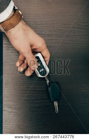Cropped Image Of Businessman Taking Off Remote Car Key From Table